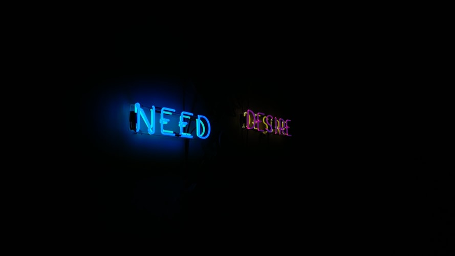 Foto tulisan neon dalam bahasa Inggris "NEED" dan "DESIRE". Ilustrasi untuk tulisan mengenai kebutuhan digital marketing Anda.